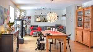 Een moderne woonkamer met een houten eettafel, een grijze bank en een kroonluchter.