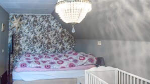 Een slaapkamer met een bed, een ledikant, een zeester decoratie en een kroonluchter.