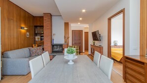 A cozy living room with a fireplace, a dining table, and a TV mounted on the wall. - 2 bedroom gorgeous apartment in Omegna (Omegna)