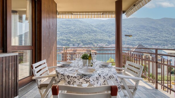 A balcony with a table set for dining, overlooking a mountainous landscape. - 2 bedroom gorgeous apartment in Omegna (Omegna)