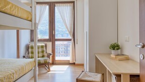 A room with a bunk bed, a chair, a desk, and a window with curtains. - 2 bedroom gorgeous apartment in Omegna (Omegna)
