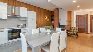 A modern kitchen with white cabinets, a built-in oven, and a dining area with a grey table and white chairs. - 2 bedroom gorgeous apartment in Omegna (Omegna)