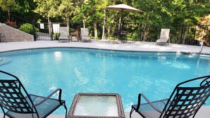 A swimming pool with two wicker chairs and a small table in the foreground. - 2BR/2.5BA, clean hot tub, spa tub, 1 mi to Pkway,10min to GSMNP, arcade,fire pit (Pigeon Forge)