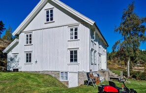 A large, white, two-story building with a steep gable roof, surrounded by a well-maintained lawn and trees. - 3 bedroom beautiful home in Bjelland (Bjelland)