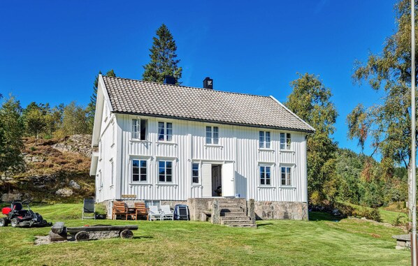 A white two-story house with a tiled roof, a stone staircase, and a sign reading "ROYNESDAL". - 3 bedroom beautiful home in Bjelland (Bjelland)