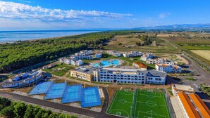 An aerial view of a coastal resort with multiple buildings, a large swimming pool, tennis courts, and a soccer field. - Nice apartment in Scanzano Jonico (Scanzano Jonico)