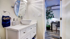 Un bagno con un mobile lavabo bianco, un ampio specchio, un lavandino bianco e un porta asciugamani.
