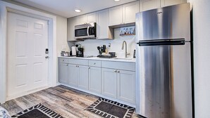 Una cucina moderna con mobili bianchi, elettrodomestici in acciaio inossidabile e pavimento in legno.