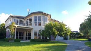 A two-story house with a balcony, large windows, and a driveway. - Large & Luxurious Family Home in a Private and Peaceful area  (Rotorua)