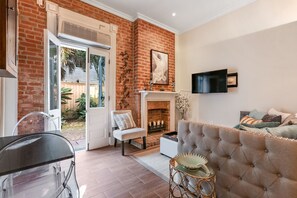A living room with a fireplace, a TV mounted on the wall, and a sofa with cushions.