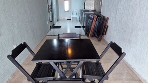 Een eethoek met een centrale tafel en stoelen, een metselwerk muur en een plafond met zichtbare balken.