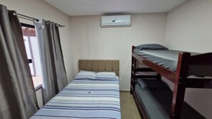 Eine kleine, einfache Unterkunft mit Etagenbett, Einzelbett und Decken-Klimaanlage.