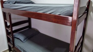 Een stapelbed met een houten frame en grijze beddengoed.