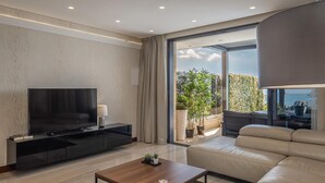 Una sala moderna con una televisión de pantalla plana, una mesa de centro y un sofá.