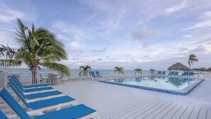 Un espace aménagé au bord de la piscine, avec des chaises longues et une piscine, offrant une vue sur la mer.
