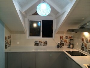 A kitchen with a window, a hanging light fixture, and a coffee machine.