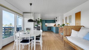 Una cocina moderna con armarios color turquesa, una mesa de comedor de madera con sillas blancas y una cama de madera con almohada azul.