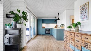 Una cocina con piso de madera, estufa, gabinetes y plantas en macetas.
