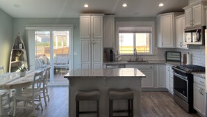 Una cocina moderna con armarios blancos, encimera de granito y electrodomésticos de acero inoxidable.