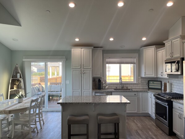 A modern kitchen with white cabinets, a granite countertop, and stainless steel appliances.
