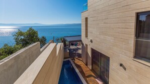 Un bâtiment moderne doté d’une piscine, d’une terrasse en bois et offrant une vue sur la mer.