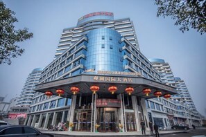 Un hotel de varios pisos con fachada curva, amplias ventanas y una entrada destacada con señalización.