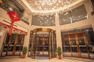 A hotel lobby with a revolving door, large windows, and potted plants.