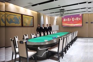 A conference room with a green pool table, white chairs, and a large screen displaying text.