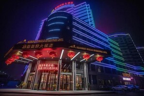 Un hôtel doté d’une entrée imposante, d’une enseigne lumineuse et d’une architecture moderne.