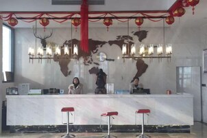 Zona de recepción con mostrador de mármol, taburetes rojos y un mapa mundial de fondo.