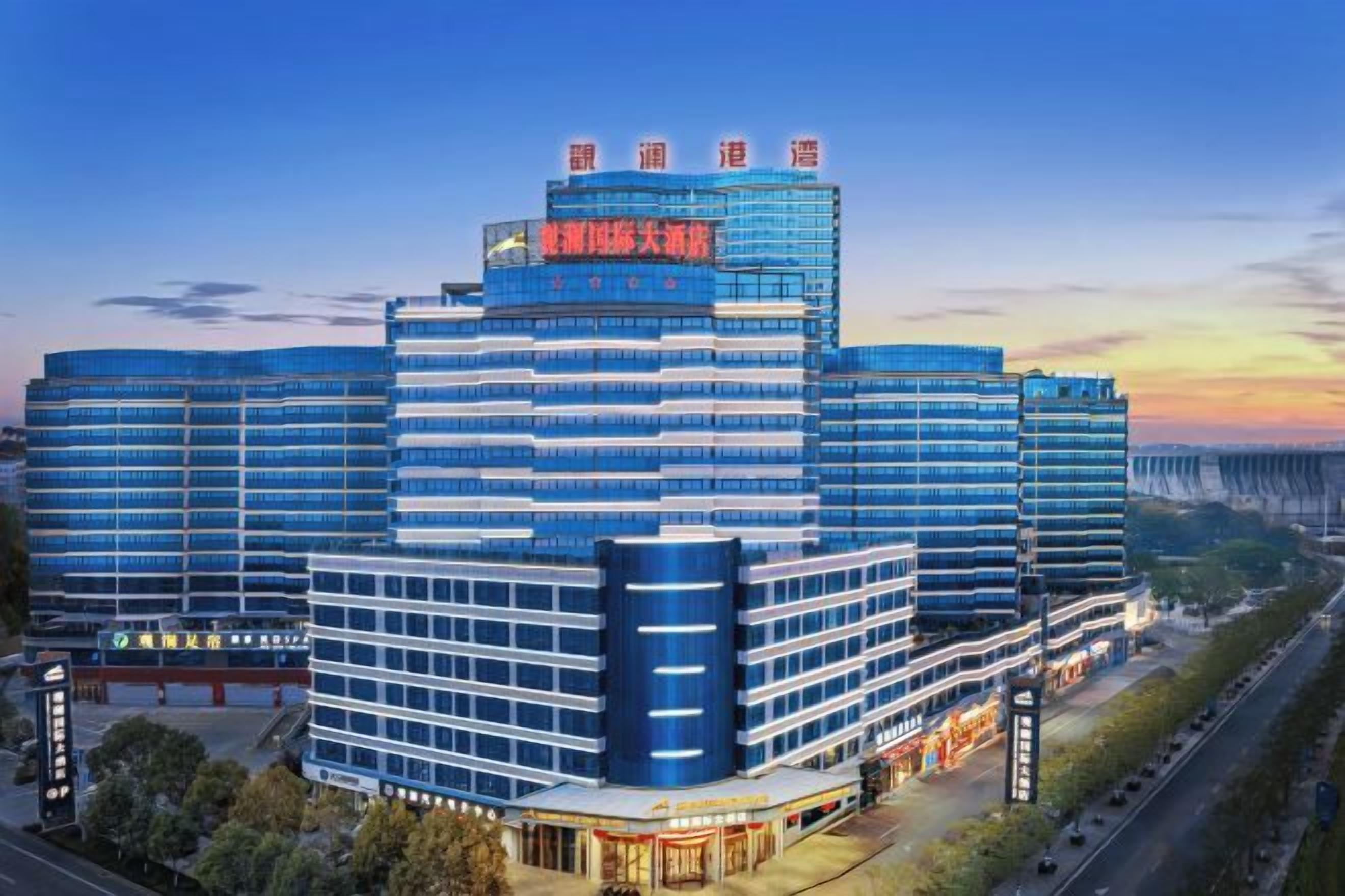 A multi-story hotel with a modern design, featuring a prominent entrance and a large parking area.