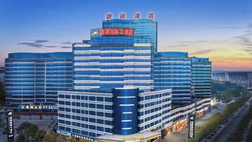 A multi-story hotel with a modern design, featuring a prominent entrance and a large parking area.