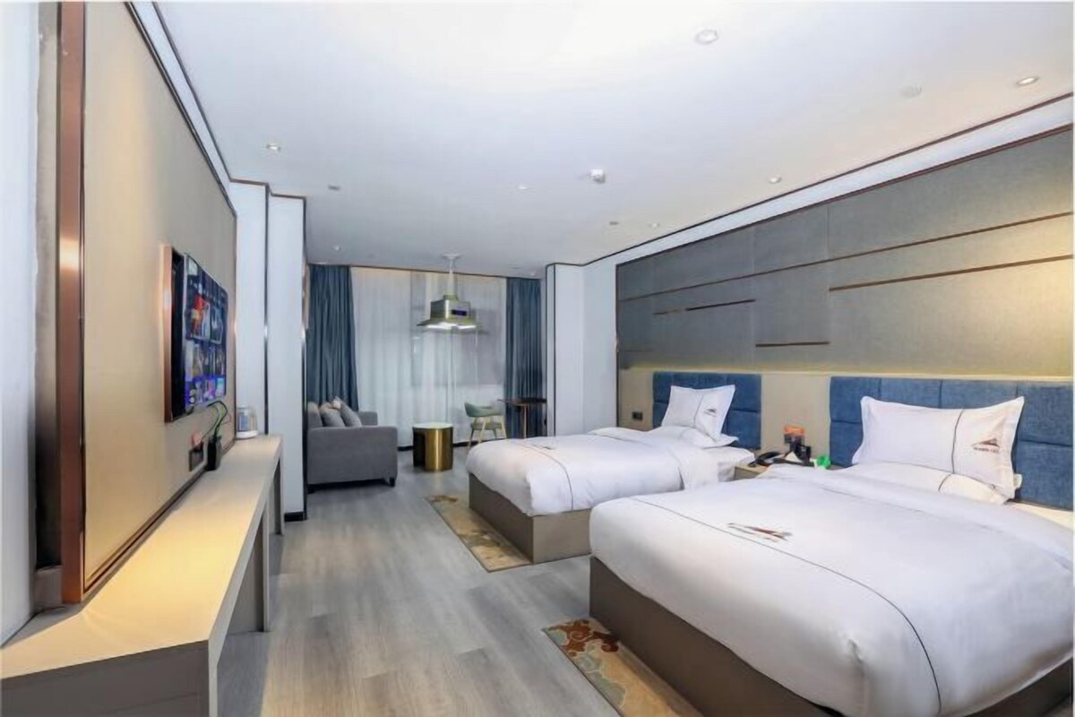 Een moderne hotelkamer met twee bedden, een bank, een bureau en een televisie.
