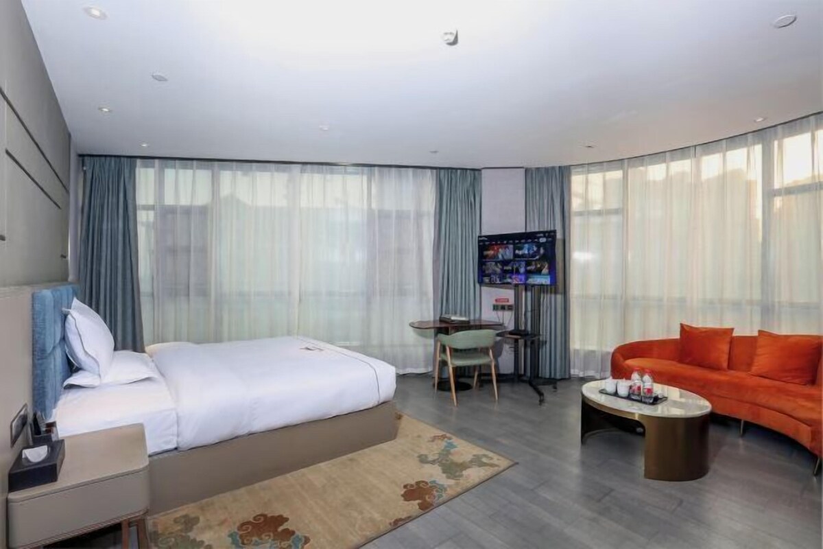 Een hotelkamer met een bed, een bureau, een televisie, een bank en een salontafel.