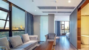 A modern hotel room with a sofa, armchairs, a wooden coffee table, and large windows offering a city view. - Danjiangkou Guanlan International Hotel（Hanjiang Avenue storefront） (Danjiangkou)