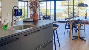 Een moderne keuken met een groot eiland, een spoelbak en een eethoek met stoelen en een tafel.