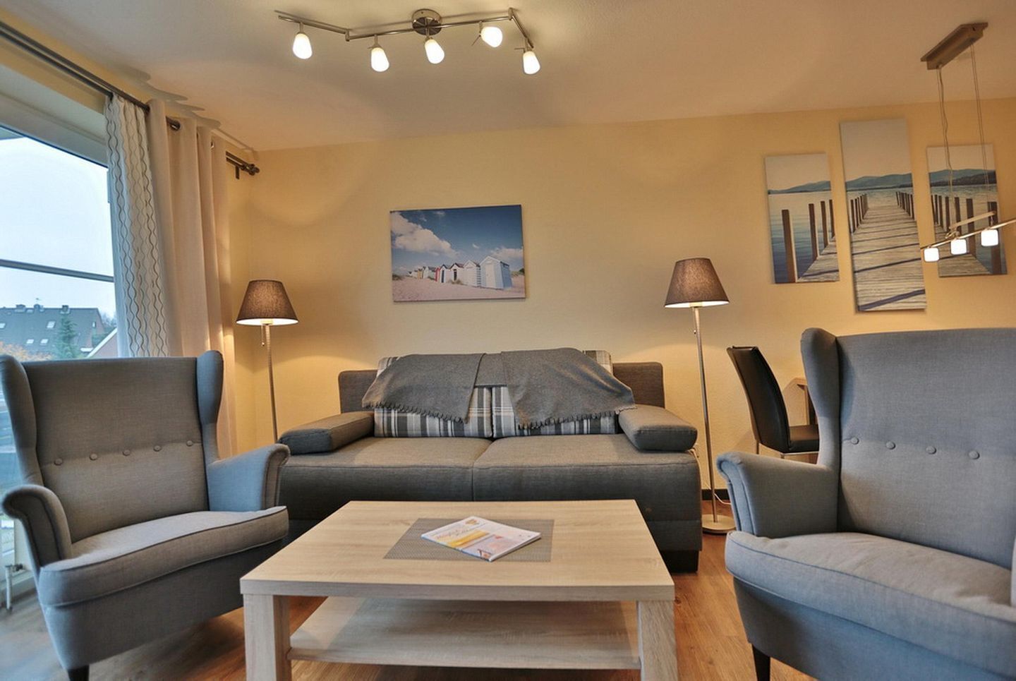 A living room with a sofa, two armchairs, a coffee table, and a painting on the wall.