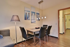 Un coin repas comprenant une table, des chaises, une lampe et des œuvres d’art accrochées au mur.