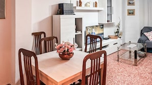 Un salon moderne comprenant une table à manger, des chaises, un téléviseur et une table basse en verre.