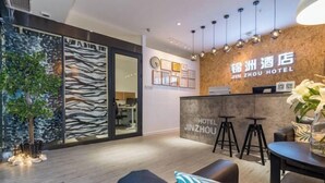 Zona de recepción de un hotel de diseño moderno, con un muro de madera con cuadros enmarcados, una mesa de recepción y un área de descanso con taburetes.