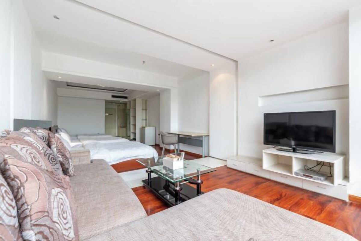 A modern hotel room with a sofa, a TV, a desk, and a bed.