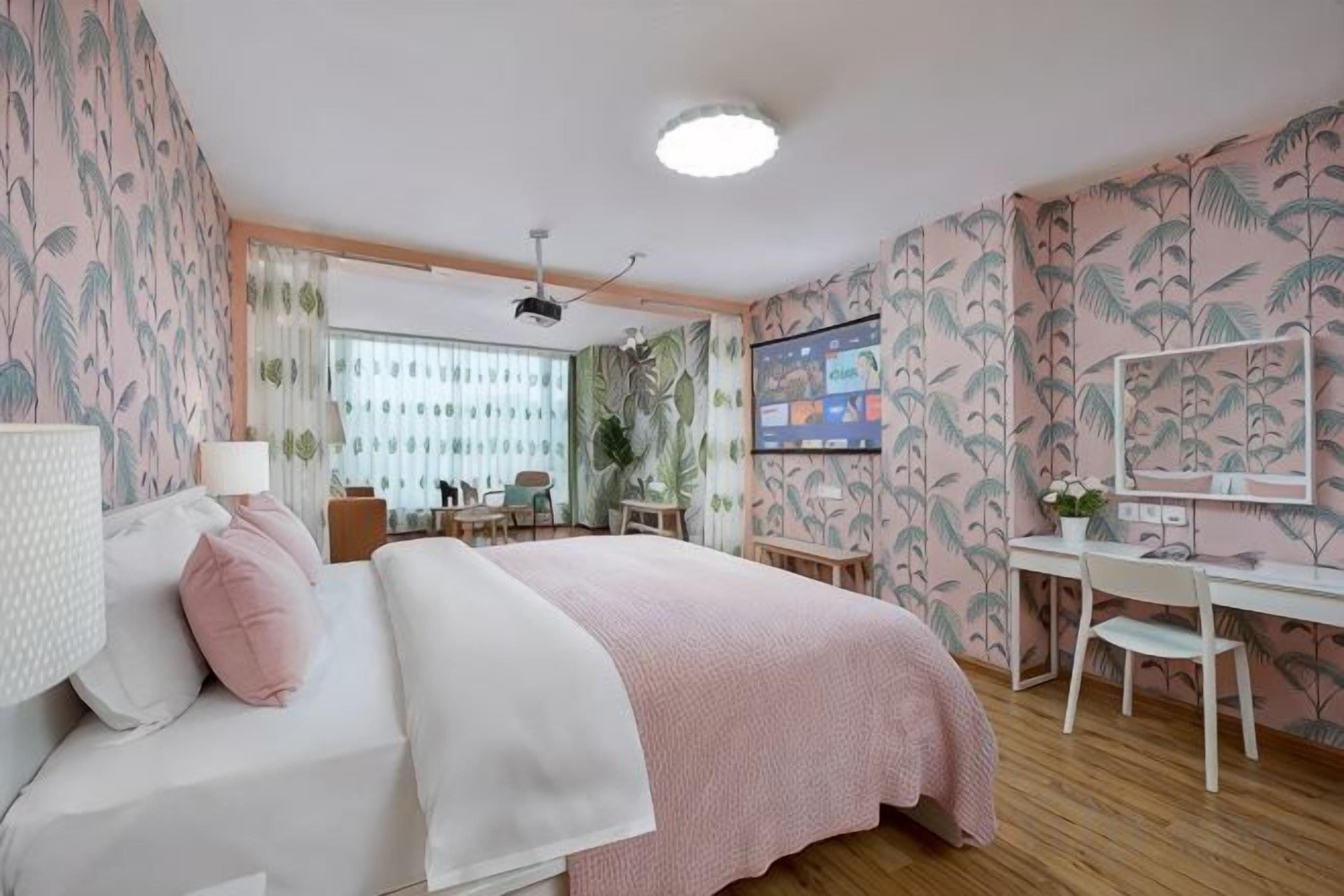 A bedroom with a bed, desk, and chair, a window with curtains, and a ceiling fan.