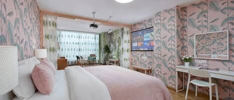 A bedroom with a bed, desk, and chair, a window with curtains, and a ceiling fan.
