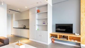 A modern living room with a flat-screen TV, wooden TV stand, and a built-in shelf unit.