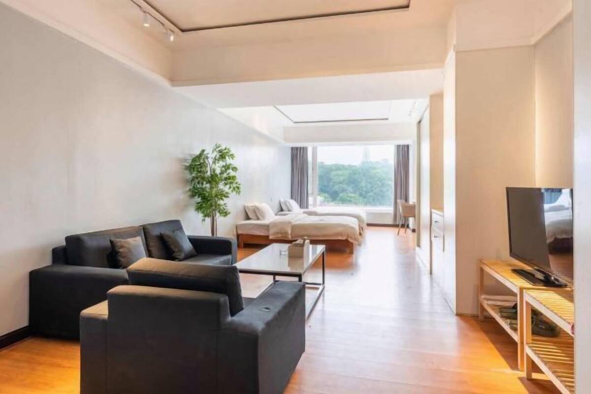 Un saló modern amb un sofà, una taula de centre, un televisor i vista d'una habitació amb un llit i una planta.
