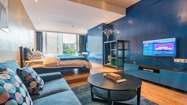 Una sala de estar moderna con un sofá, una mesa de centro, un televisor y una cama.