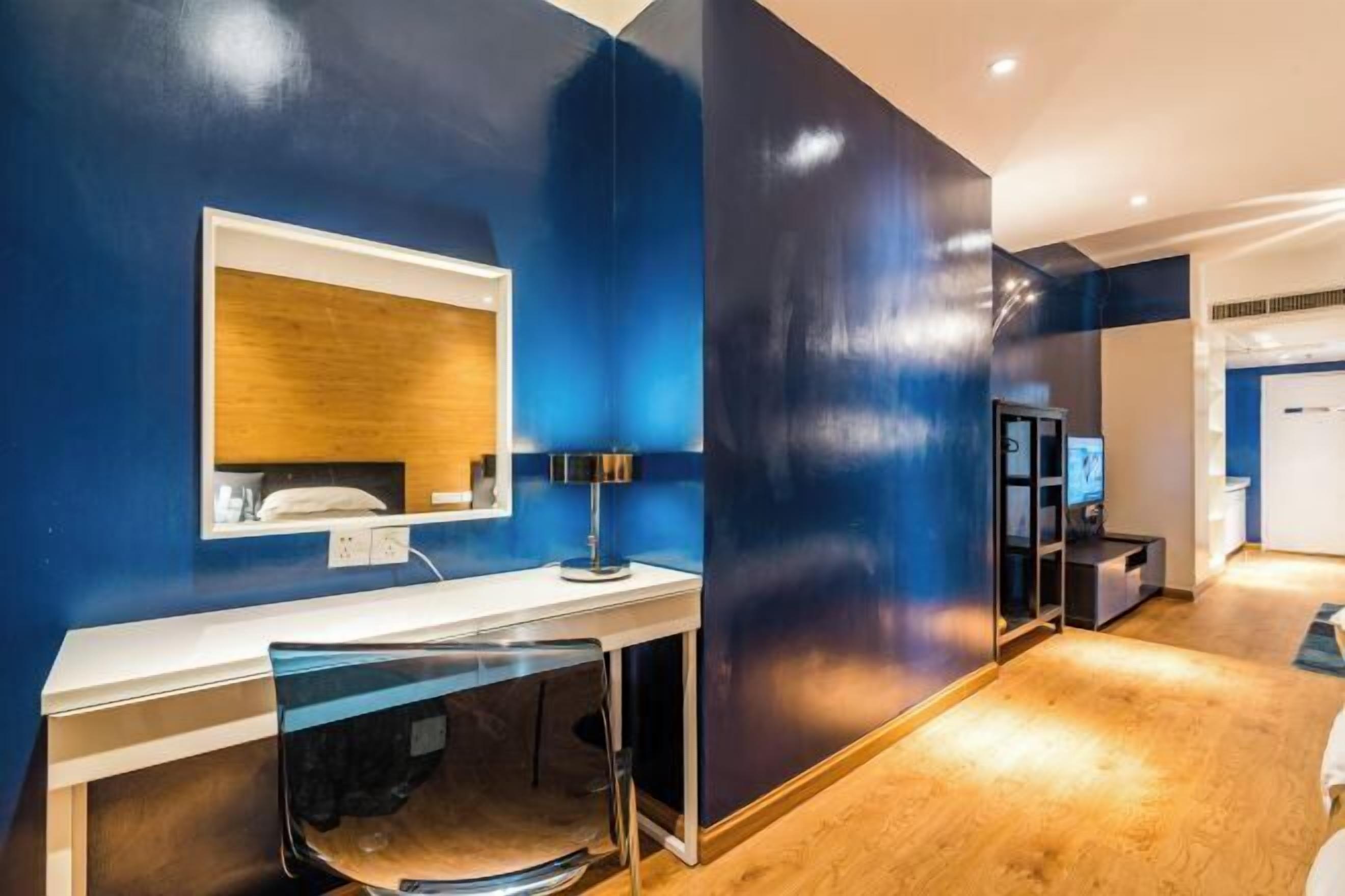 Une chambre d’hôtel moderne, dotée d’un grand miroir, d’un bureau et d’une télévision.