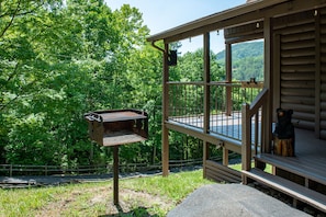 Escape to a serene natural setting surrounded by lush greenery, where a cabin awaits with a welcoming porch and outdoor space to unwind.