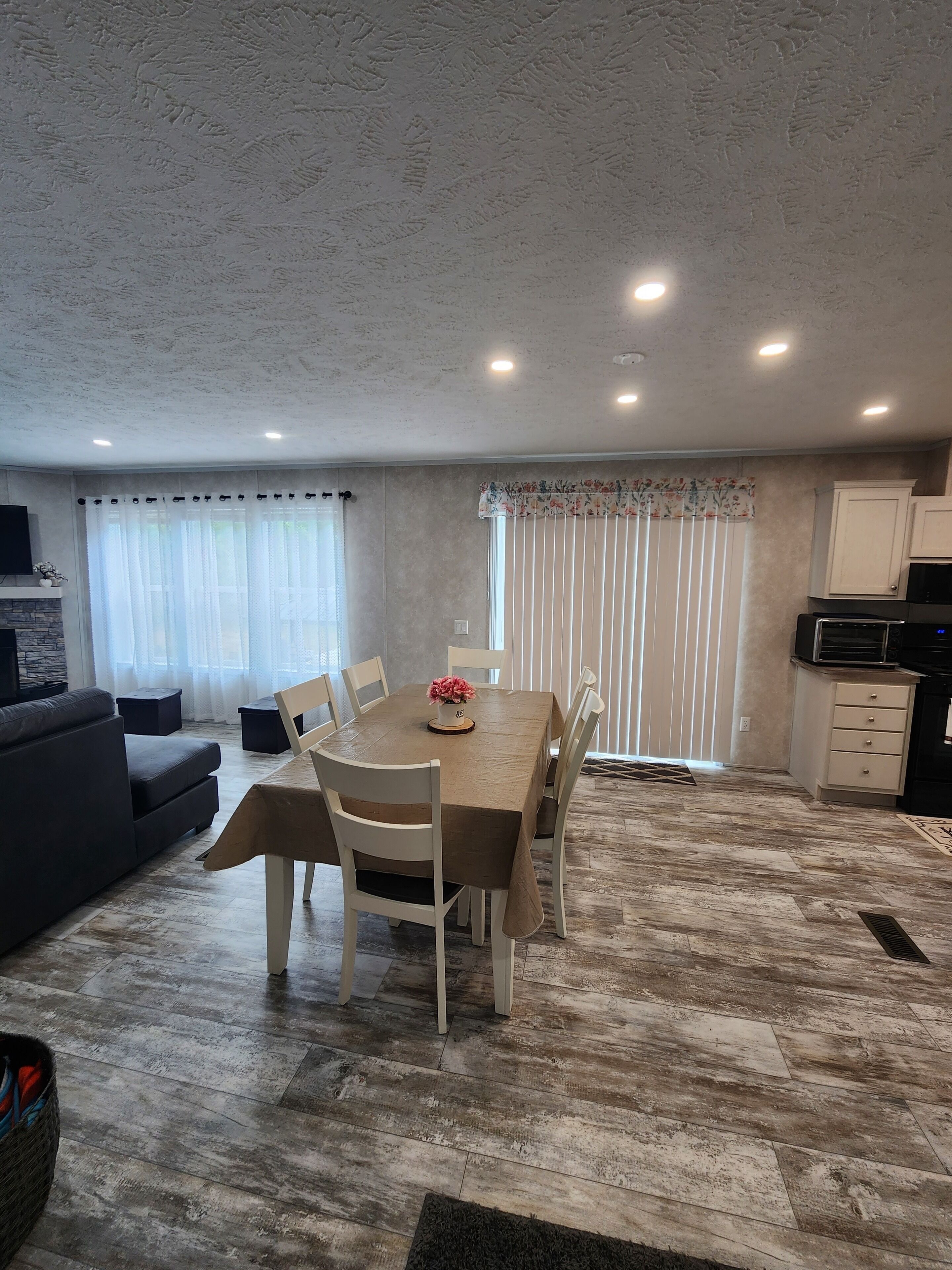 A modern living room with a dining area, a kitchen, and a fireplace.