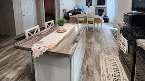A spacious kitchen with a central island, wooden flooring, and modern appliances. - Cozy Cabin with a Hot Tub! (Wisconsin Dells)